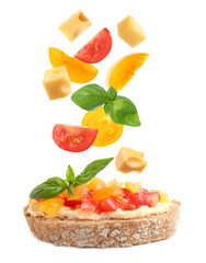 Tasty bruschetta with flying ingredients on white background