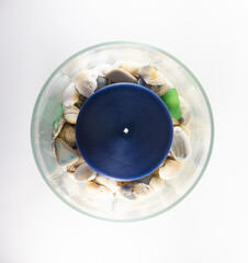 Blue candle in a vase full of seashells
