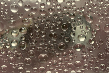Rounded ice particles are located on a brown- beige mirror ice surface. Close-up. 