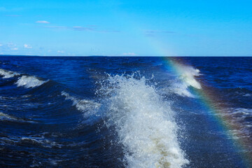 Trail from a motor boat racing at high speed, water splash, rainbow