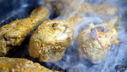 Smokey Chicken tangdi or Tangri kebab or kabab being cooked in a grill pan