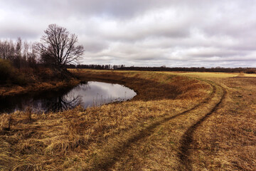 Autumn landscape with a view of the meadow and the river. Gloomy pre-rain sky in the countryside....