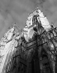 t a monochrome view of the towers at the entrance to york minster in sunlight against a cloudy sky