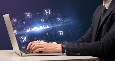 Businessman working on laptop with SUPER SALE inscription, online shopping concept