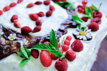 homemade birthday cake with summer berries decoration. flowers and berries on a home made cake.13th birthday selebration. teenagers party. close up view. selective focus