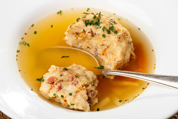 single speckknoedel in soup on wood