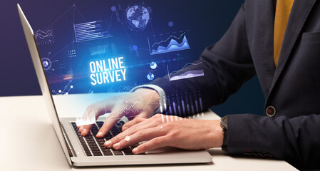 Businessman working on laptop with ONLINE SURVEY inscription, new business concept