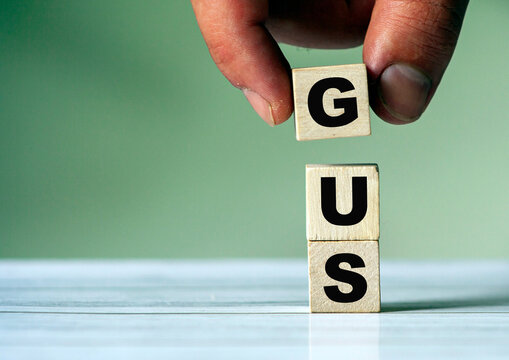The hand puts the cube block with the inscription GUS.