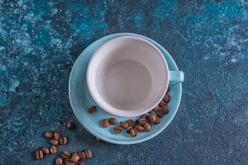 Obraz na płótnie Canvas Empty blue cup for coffee and coffee beans on blue background,flat lay.