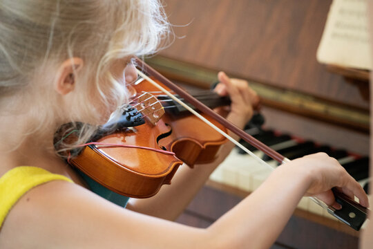 little girl concentrating on playing a small violin, suzuki lessons, horizontal shape, music lesson
