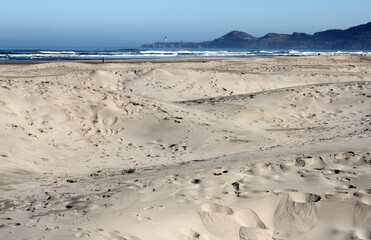 Beach scene with blue and white surf, crashing waves, and smooth sand dunes