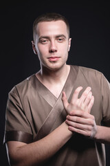 Portrait of a strong and large male masseur in special clothes with a finger at the temple reads...