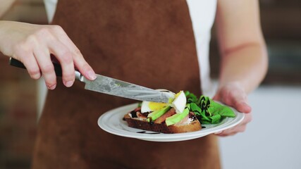 Woman holding a bruschetta with avocado, poached egg, salmon and cottage cheese