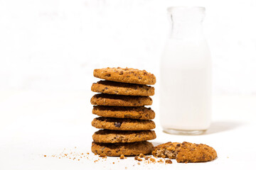 oatmeal cookies with chocolate chips on a white background and a bottle of milk, closeup