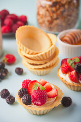 Delicious mini tart tartlets with fresh berries on blue background