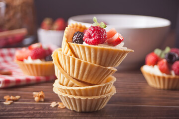 Delicious mini tart tartlets with fresh berries on wooden background