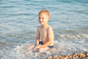 Boy having fun in sea or ocean waves in a summer sunny day. Ocean coast and beach. Active lifestyle and recreation concept