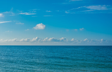 Obraz premium Blue sea surface extending to the horizon under a cloudy sky.