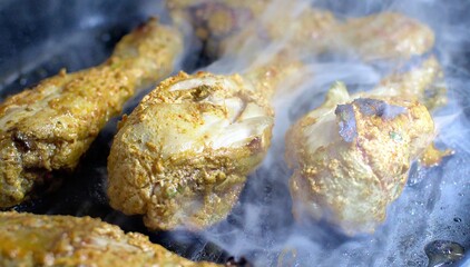 Smokey Chicken tangdi or Tangri kebab or kabab being cooked in a grill pan