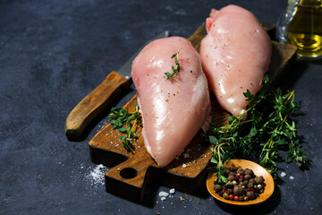 raw chicken breast and fresh thyme on a cutting board