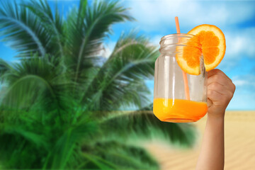 cheerful kid holds a glass jar in his outstretched hand with orange juice from an orange or lemon with a straw, the concept of a healthy diet, vitamins, life style