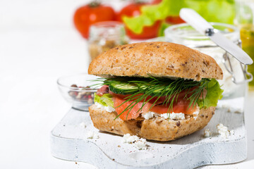 sandwich with salted fish, fresh vegetebles and cream cheese on white wooden board