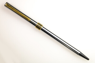 metal pen, with golden and silver colors, in a transversal position, on a white background