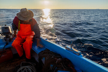 Silhouette of fisherman on boat during sunset, on Adriatic sea, island Vis, Croatia