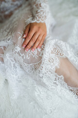 beautiful female hand with gentle manicure lies on her knee, white lace clothing on  body, close-up