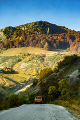 Orange van driving through mountains in autumn