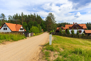 Fototapeta na wymiar Rural road and traditional style rustic houses in Wygryny village near lake Nidzkie, Mazury Lake District, Poland