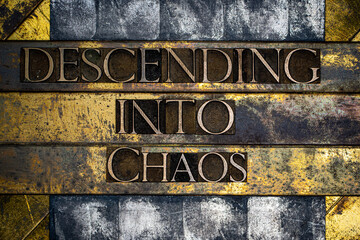 Descending Into Chaos text formed with real authentic typeset letters on vintage textured silver grunge copper and gold background