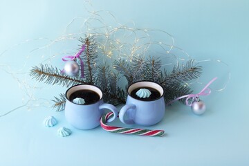 Merry Christmas, two cups of coffee, meringues, festive decor, illumination, mint color background, concept of home comfort and congratulations on winter holidays