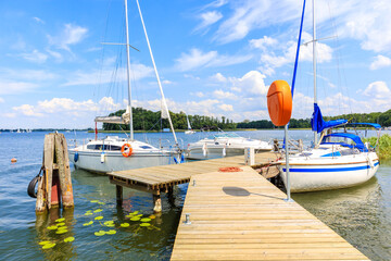 Boats anchoring at pier in Wierzba sailing port on Lake Beldany on summer sunny day, Masurian...