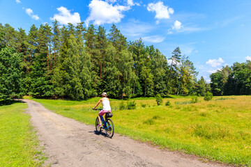 Naklejka premium Young woman cycling on bike on forest road near Mikolajki town, Masurian Lakes, Poland