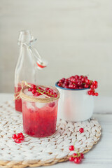 Glass jar of red currant soda drink on white wooden table. Summer healthy detox lemonade, cocktail or another drink background. Low alcohol, nonalcoholic drinks or healthy diet concept.