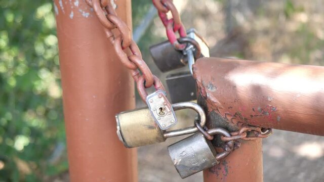 Smooth pan clip of locks on brown gate posts with chain link, at park school closed during coved-19 coronavirus pandemic lockdown. Shot in 4K 60fps.