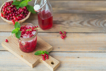 Fresh red currant cocktail in glass jar. Summer pink cocktail with red currant and ice cubes on wooden background mockup with copy space for text.