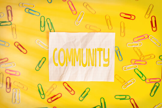 Word writing text Community. Business photo showcasing group of showing with a common characteristics living together Flat lay above empty paper with copy space and colored paper clips