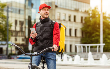 Courier Man Using Mobile Phone Delivering Food Riding Bicycle Outdoors