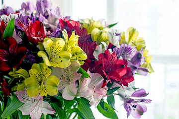 Alstroemeria bouquet of flowers in a vase by the window. Beautiful bouquet of colorful flowers in the apartment by the window.