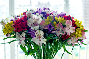 Alstroemeria bouquet of flowers in a vase by the window. Beautiful bouquet of colorful flowers in the apartment by the window.