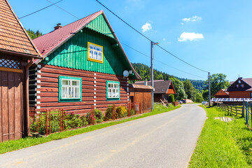 Old traditional rural wooden house along street in Osturnia village in Tatra Mountains on beautiful summer sunny day, Slovakia