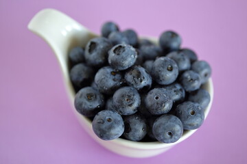 blueberries in a bowl close up isolated on purple background