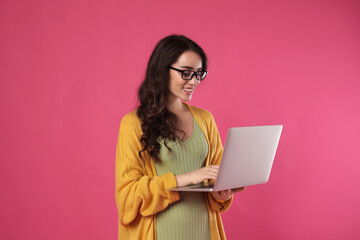 Young woman with laptop on pink background