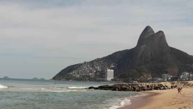 Ipanema and Leblon beach in Rio de Janeiro during COVID-19 coronavirus outbreak with city mountain Two Brothers in the background and boulder rocks marking drainage canal in the foreground