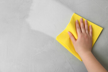 Woman wiping grey table with rag, top view. Cleaning service