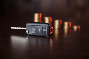 Car key and coins on wooden background, concept photo for car finance industry.