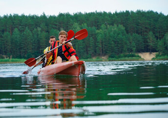 two guys in a red kayak on the river, in life jackets