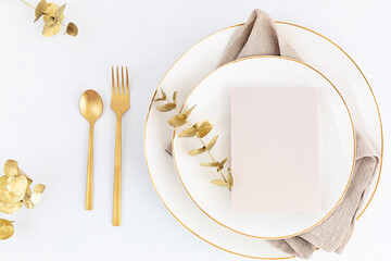 Festive christmas, wedding, birthday table setting with golden cutlery and porcelain plate. Blank card mockup. Restaurant menu template. Flat lay, top view